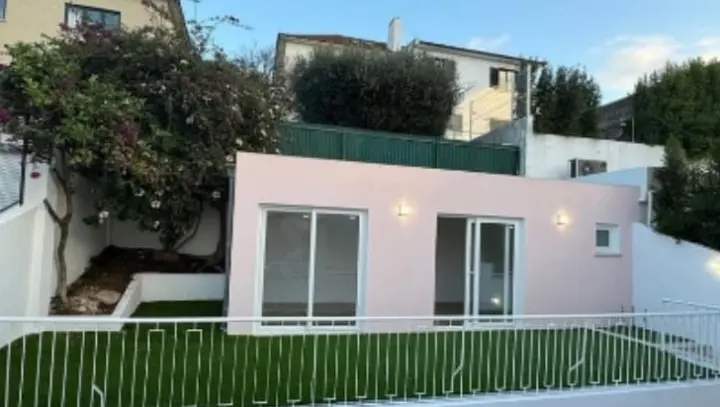Jardim com relva e o anexo com portas de vidro.