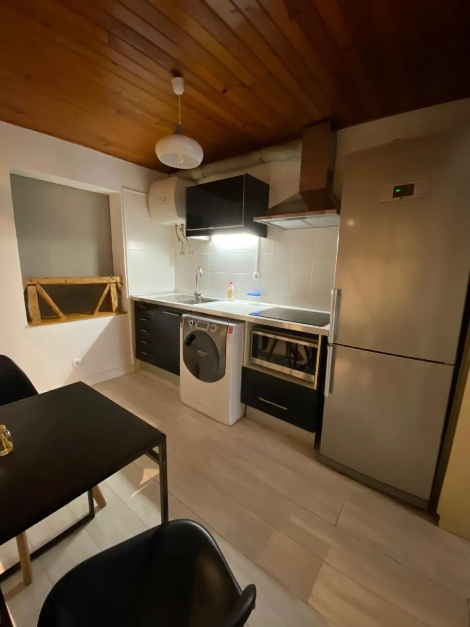 Cozinha com frigorífico, micro-ondas e máquina de lavar roupa.