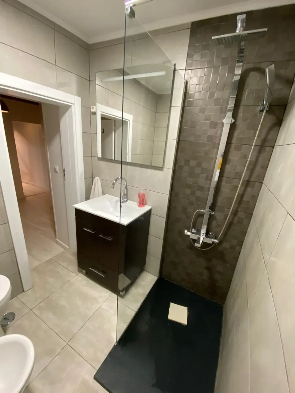 Casa de banho com base de duche, divisória de vidro e móvel de lavatório.
